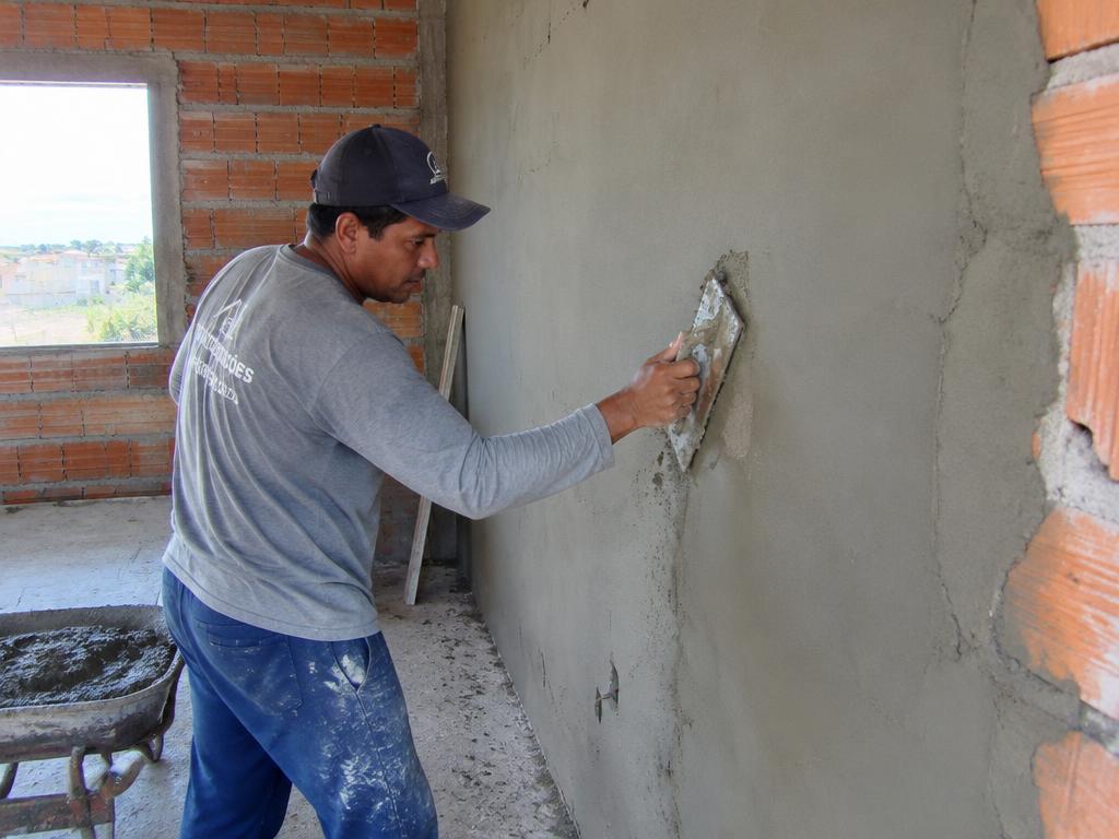 Pedreiro aplicando reboco em parede de alvenaria